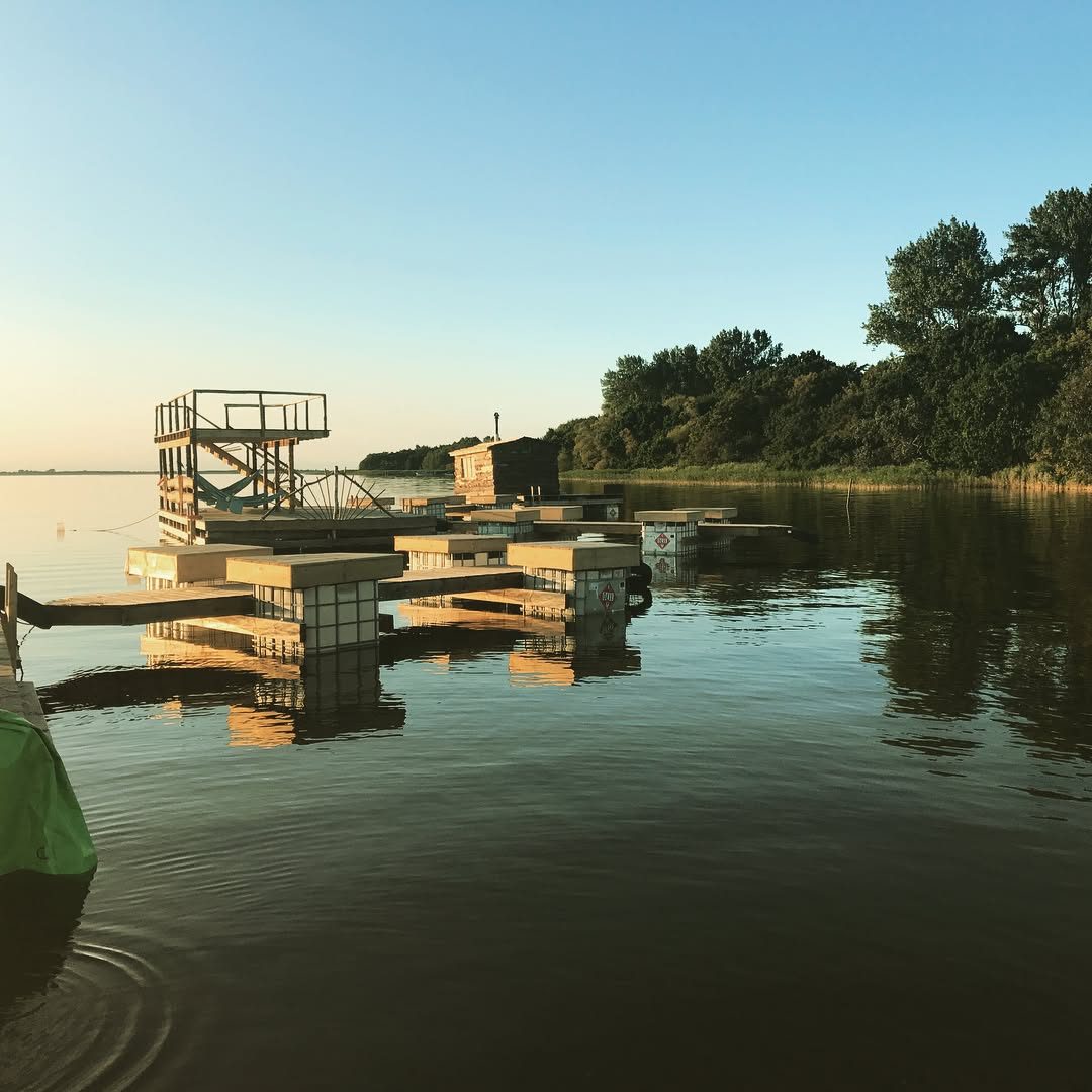 Schwimmende Badeinsel mit Sprungturm aus Holz auf einem See bei Sonnenuntergang