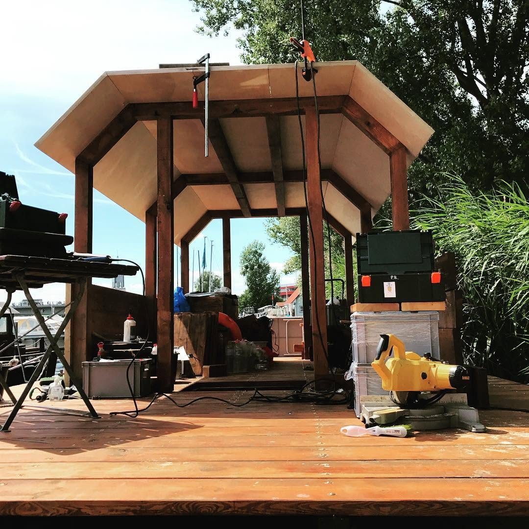 Sechseckiger Holzpavillon im Bau auf einem schwimmenden Floß am Wasser